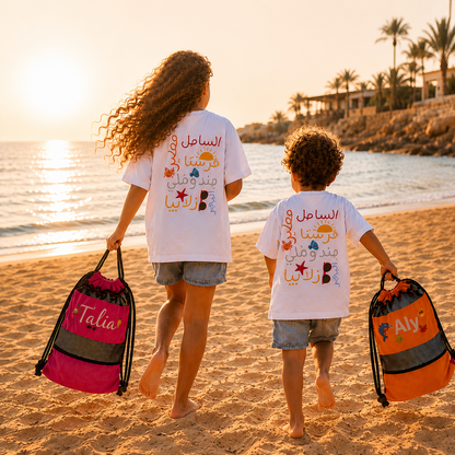 Two children on a beach with personalized bags at sunset.